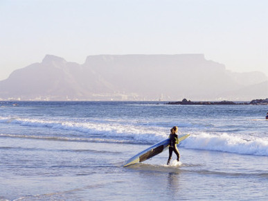 Young Woman Surfer Enters the Water of the Atlantic Ocean with Table Mountain in the Background